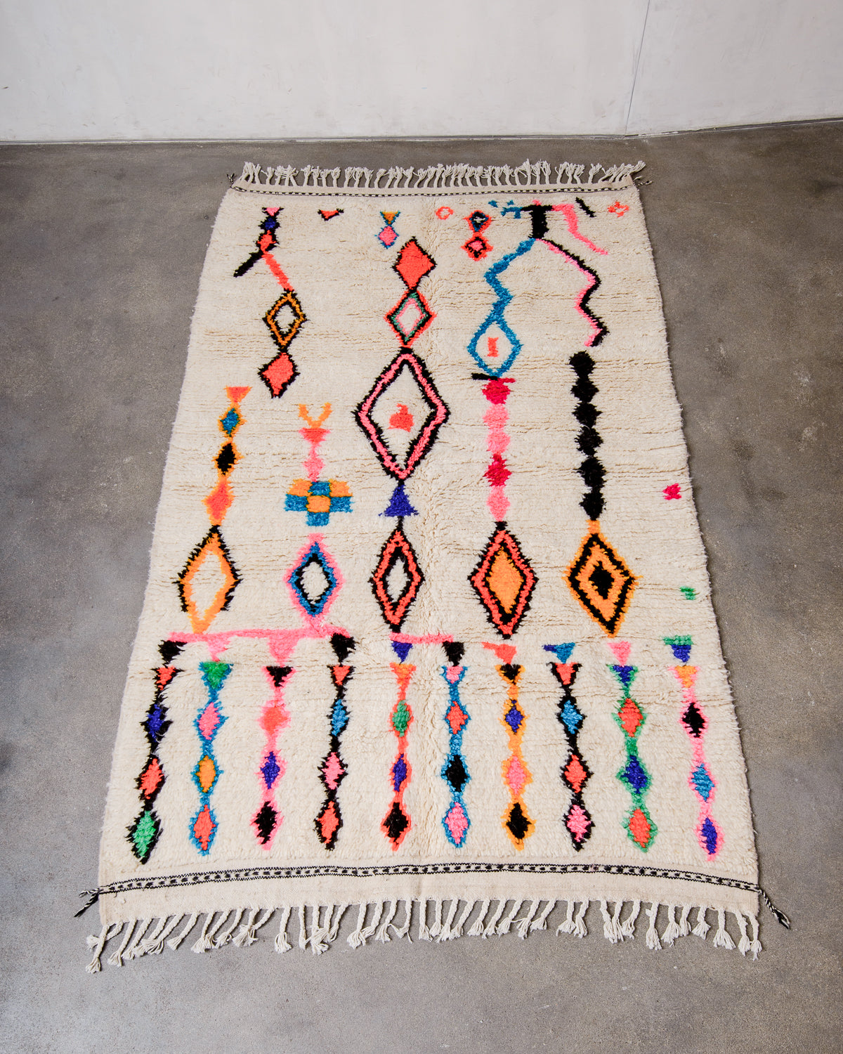 Berberlin Azilal rug made of fluffy wool and cotton, laying flat on a concrete floor.